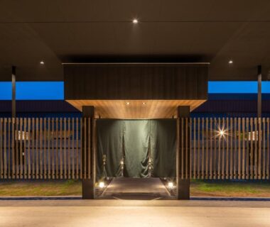 Illuminated wooden entrance with noren curtains and vertical slats at Tokachigawa Moor Onsen Seijyakubow in Hokkaidō