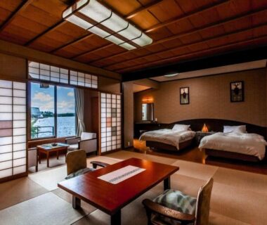 Spacious tatami seating area, low table, twin beds and shoji screens with waterfront view at Tokigasane, Ishikawa