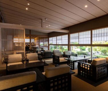 Spacious ryokan lounge with wooden lattice seating and garden views through shoji style windows at Tokiwa Bekkan Hyōgo