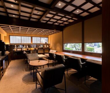 Indoor lounge with armchairs, low tables, lattice ceiling and window seating at Tokiwa Bekkan, Hyōgo, Kansai