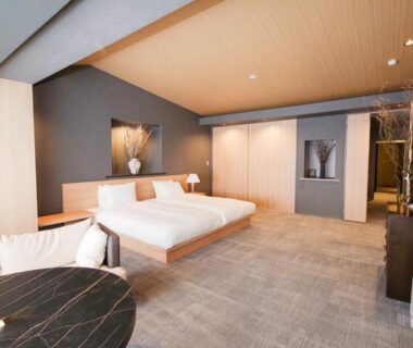 Modern guest room with twin beds, low platform, seating area and wooden ceiling at Tokiwa Hotel Yamanashi