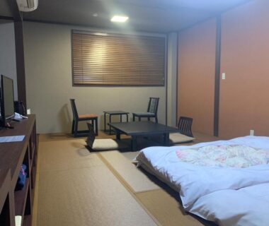 Tatami room with futon, low table and chairs, wooden blinds at Tokiwa Ryokan in Tochigi