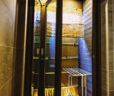 White bathtub beside tall glass doors opening to a wooden courtyard with bamboo fence at Louis House Tokyo