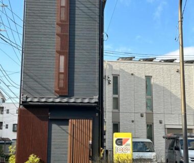 Narrow three-story townhouse facade with wooden panels and street signage outside Louis House Tokyo