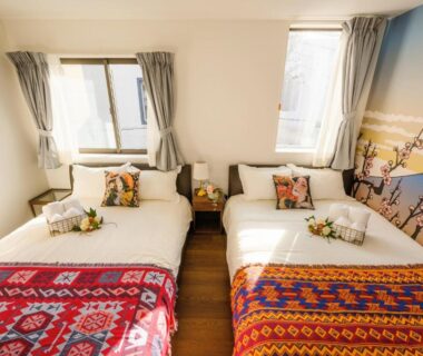 Bright twin bedroom with colorful patterned throws at Louis House in Tokyo