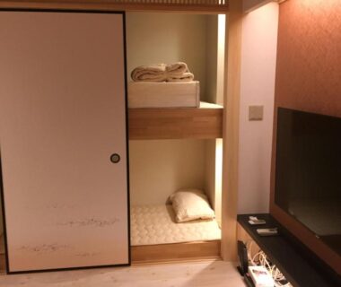 Stacked futon in alcove with fusuma sliding door and TV at Tokyo inn Sakura An, Tokyo, Japan