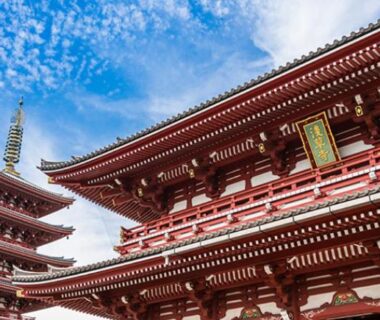 Red temple pagoda and ornate wooden halls under blue sky in central Tokyo, near Tokyo inn Sakura An