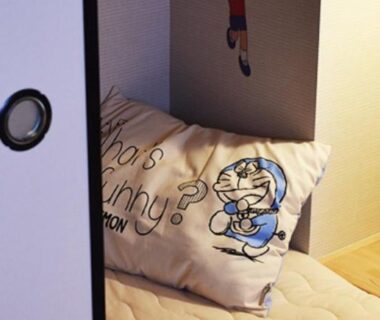 Small futon sleeping alcove with cartoon pillow, shoji sliding door and wooden floor at Tokyo Inn Sakura An, Tokyo, Japan