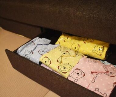 Colorful folded children's robes with bear prints in a drawer beside a tatami mat