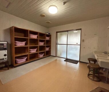 Wooden cubby shelves with baskets, wash basins and stools, frosted sliding door in Tomiya Ryokan changing area, Niigata