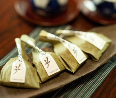 Leaf-wrapped confections on wooden tray with ceramic teacups at Tomiya Ryokan Niigata