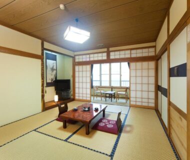 Traditional tatami room with low wooden table, zabuton cushions and shoji screens at Tomiya Ryokan in Niigata Chūbu Japan