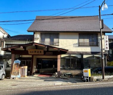 Two-story ryokan exterior with traditional entrance and signage at Tomiya Ryokan in Niigata, Chūbu region