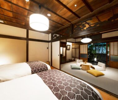 Tatami-floored room with two beds, low table, shoji screens and garden view at Tomonoura Shiomachi Hotel, Hiroshima