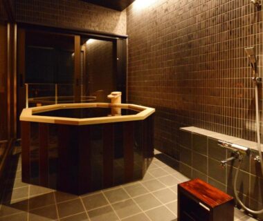 Octagonal wooden soaking tub with shower in tiled bathing room at Toriizaki Club Sushi Auberge, Chiba