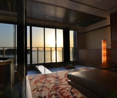 Low-seated room with patterned rug and sliding glass doors to waterfront sunset at Toriizaki Club, Chiba