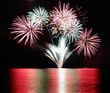 Fireworks bursting over water with bright reflections near Toya Kohan Tei Hokkaidō