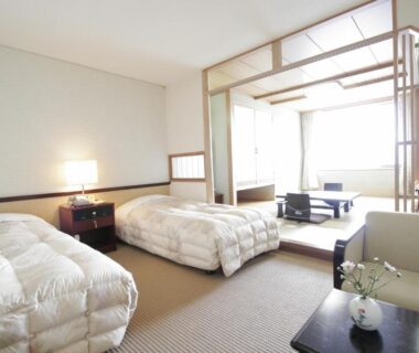 Bright room with twin beds, tatami seating area, shoji screens and low table at Toya Kohan Tei in Hokkaidō