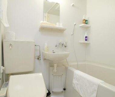Compact white bathroom with toilet, sink, mirror, bathtub and toiletries at Toya-onsen Hotel Hanabi Hokkaidō Japan