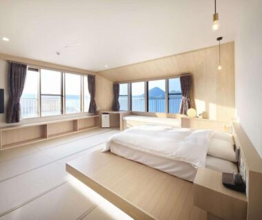 Bright tatami-style room with low platform bed and large windows overlooking lake and distant hills