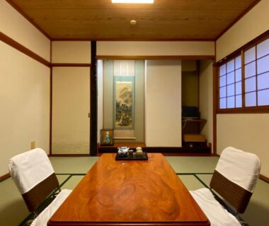 Traditional tatami room with low wooden table, two zaisu chairs, shoji screens and tokonoma at Toyofuku, Hyōgo
