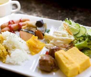 Tamagoyaki, rice, salad greens and assorted side dishes on a white plate at Toyoko Inn Maebashi
