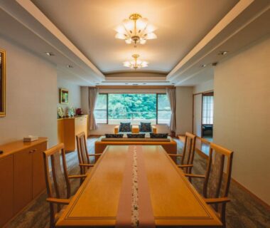 Long wooden dining table and chairs facing garden window at Tsuetate Onsen Hotel Hizenya Kumamoto Kyūshū