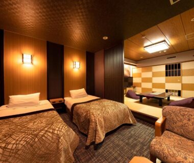 Twin room with two beds, tatami seating area, wooden accents and warm ambient lighting at Tsuetate Onsen Hotel Hizenya Kumamoto