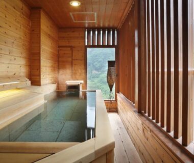 Indoor wooden bath with slatted screens and window view of trees at Tsuganoki, Tochigi