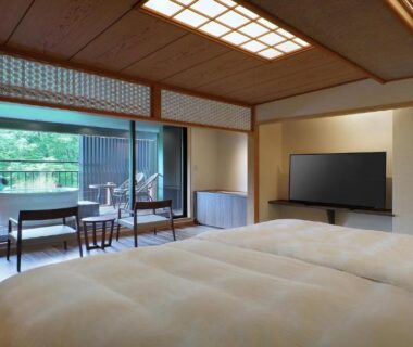 Spacious tatami room with futon beds, low table, sliding shoji doors and balcony overlooking greenery at Tsuganoki in Tochigi