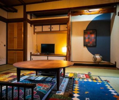 Traditional tatami room with low table and cushions, shoji screens, tokonoma alcove, warm lighting at Tsukasa Ryokan Saga