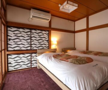 Japanese room with two low beds, shoji screens and wooden accents at Tsukasaya Ryokan in Yamagata