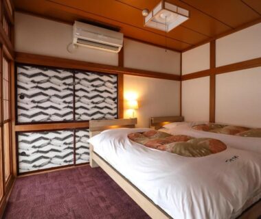 Japanese room with two low beds, shoji screens and wooden accents at Tsukasaya Ryokan in Yamagata