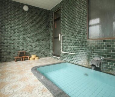 Tiled indoor bathing area with small stools at Tsukasaya Ryokan in Yamagata