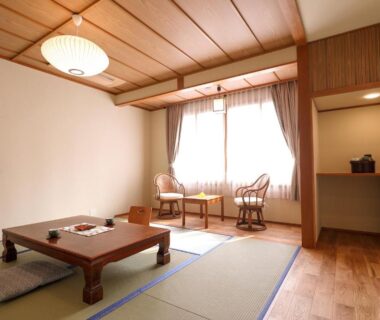 Traditional tatami room with low table, floor cushions, wooden ceiling and window seating at Tsukasaya Ryokan, Yamagata
