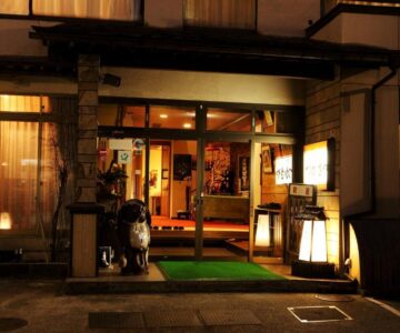 Lantern-lit main entrance with glass doors and warm interior at Tsukasaya Ryokan in Yamagata, Tōhoku, Japan