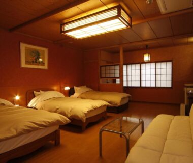 Warm tatami room with three beds, shoji screens, sofa and low table at Tsuki no Shizuka in Nagano, Chūbu
