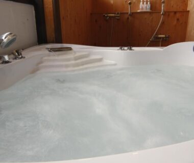 Bubbling indoor bathtub with wooden paneling and shower at Tsuki no Shizuka in Nagano