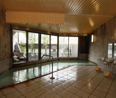 Tiled indoor onsen bath with wooden walls, stools and windows at Tsuki no Shizuka, Nagano