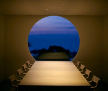 Long wooden table and chairs framed by round window, Tsuki to Maguro Ishigami, Shizuoka