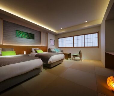 Twin beds on tatami floor with shoji window, low seating and soft ambient lighting at Tsukinoike, Yamagata