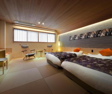 Tatami room with twin low beds and lounge chair at Tsukinoike, Yamagata