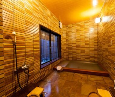 Tiled indoor bathing area with soaking tub, showers and stools at Tsuruya Ryokan in Hyōgo, Kansai