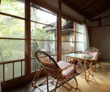 Wicker chairs and small table on tatami beside shoji windows at Tsuruya Ryokan in Nagano