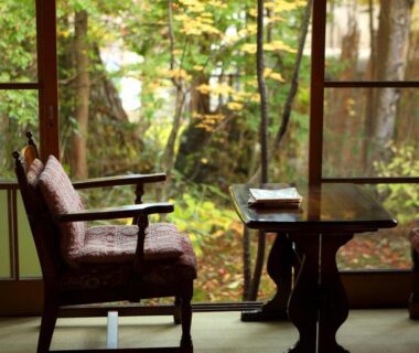 Two upholstered chairs and low table on tatami facing mossy garden through shoji doors