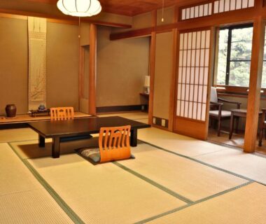Spacious tatami room with low table, shoji screens, wooden accents and window seating at Tsutaya Ryokan in Hyōgo
