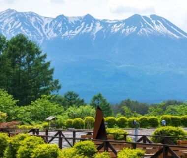Wooden terrace and garden with snow capped mountain backdrop at Tsutaya Tokinoyado Kazari Nagano