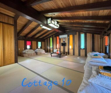 Large tatami room with futons, wooden beams and colorful window panels at Tsuyukusa, Gifu, Chubu Japan
