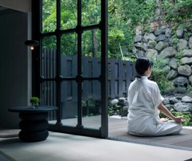 Guest in white robe seated on engawa overlooking stone garden and shoji doors at UTAHI Kyoto machiya