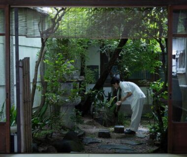 Tatami room opening to a courtyard garden with staff tending plants at UTAHI A Kyoto